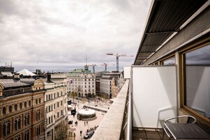 A high-rise building with a view of a cityscape, including historic architecture and construction cranes.