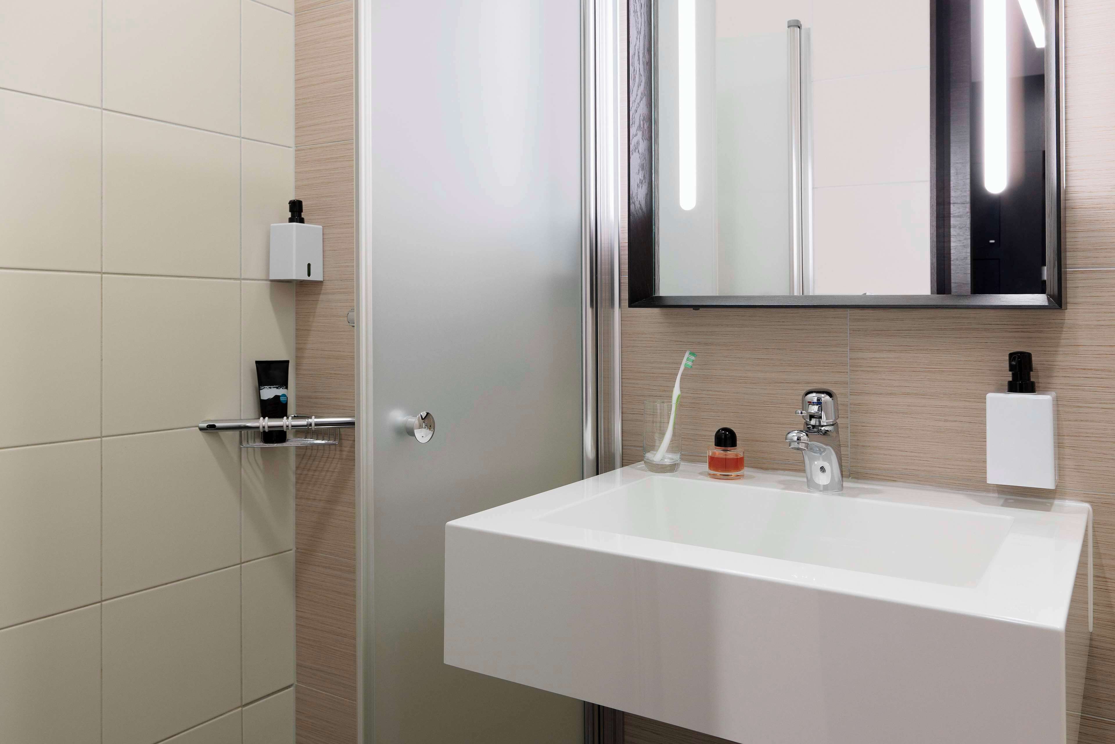 Une salle de bain moderne avec un lavabo blanc, un miroir et une douche à parois de verre.