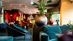 Ein modernes Interieur mit türkisfarbenen Sofas, einer dekorativen Vase mit Blumen und einer Bar im Hintergrund.