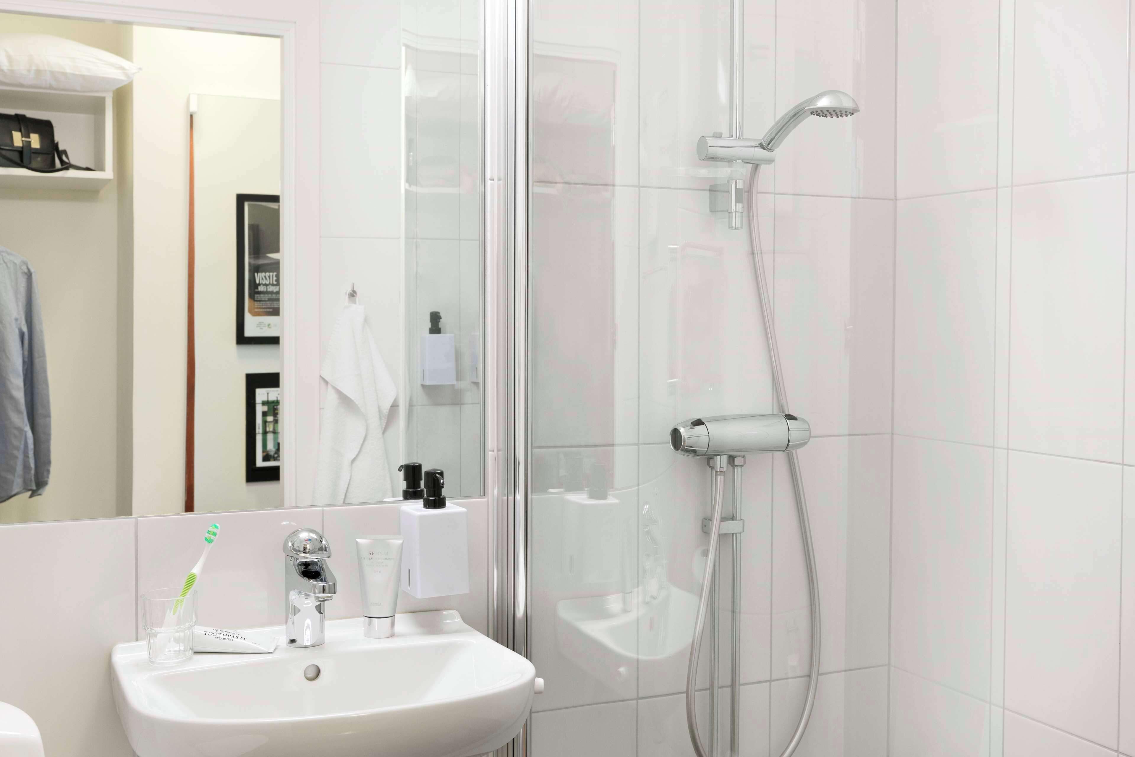 A bathroom with a white sink, a glass shower enclosure, and a mirror.