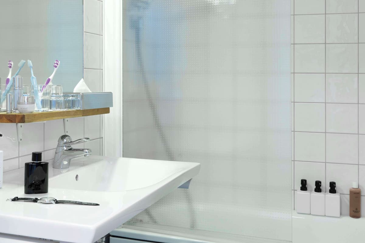 A modern bathroom with a white sink, a mirror, and a shower area.
