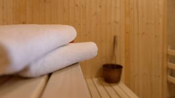 A wooden sauna with a bench and a small wooden bucket.