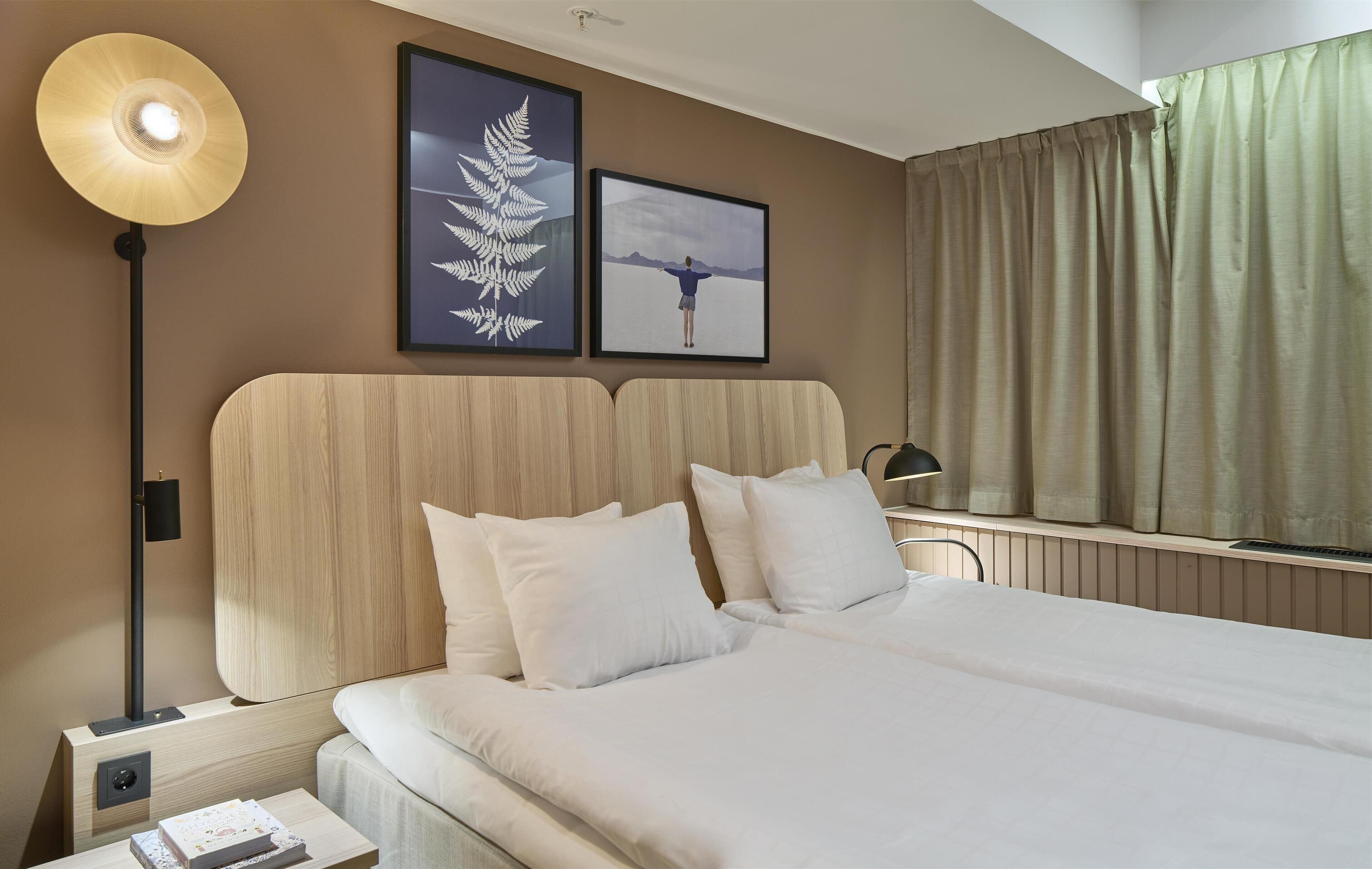 Una camera d'albergo con un letto grande, un comodino con una lampada e due quadri appesi al muro.