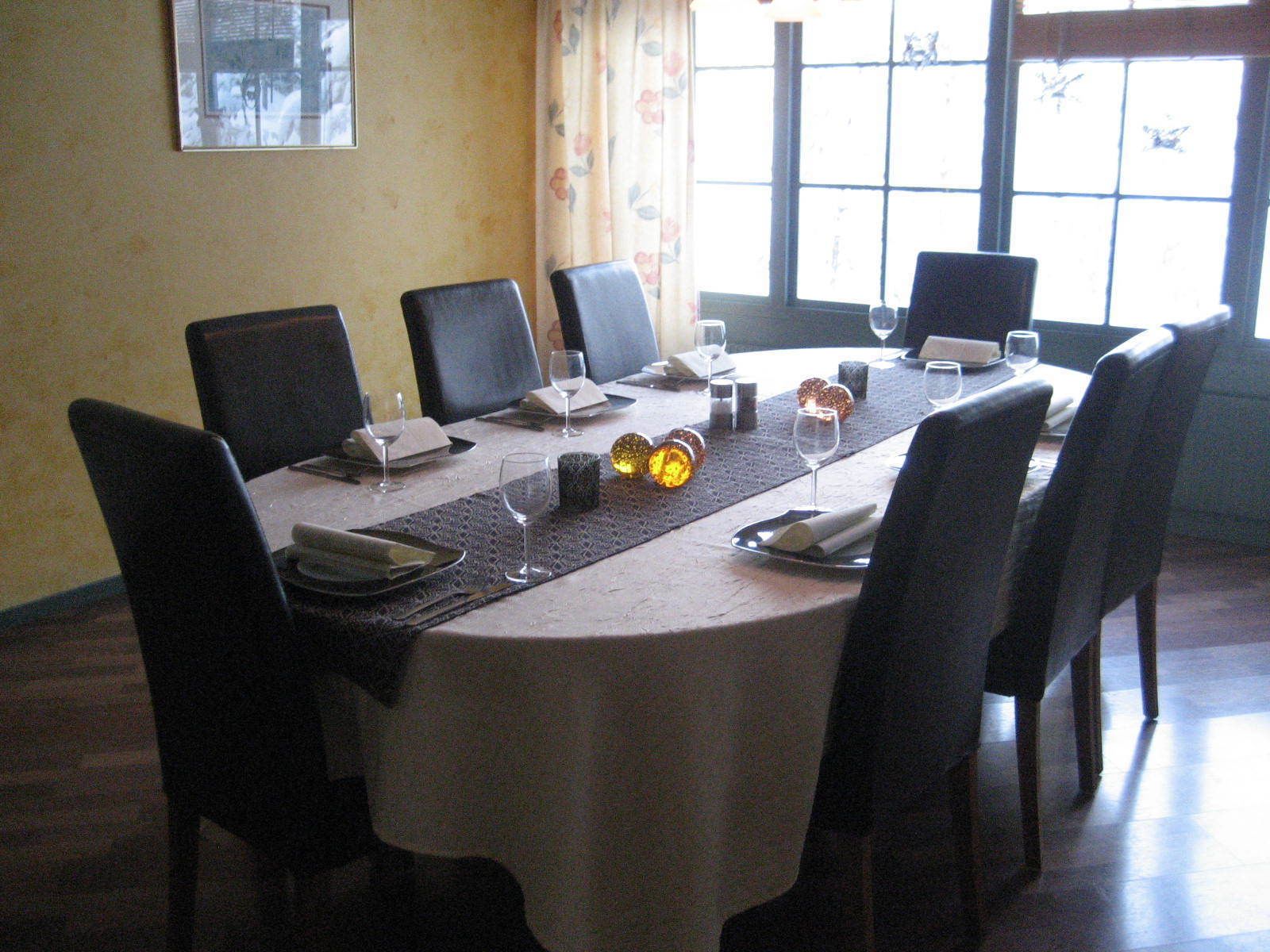 Un salón de conferencias con una mesa redonda, sillas negras y un mantel blanco.