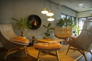 A modern interior with wicker furniture, a fireplace, and natural light from windows.