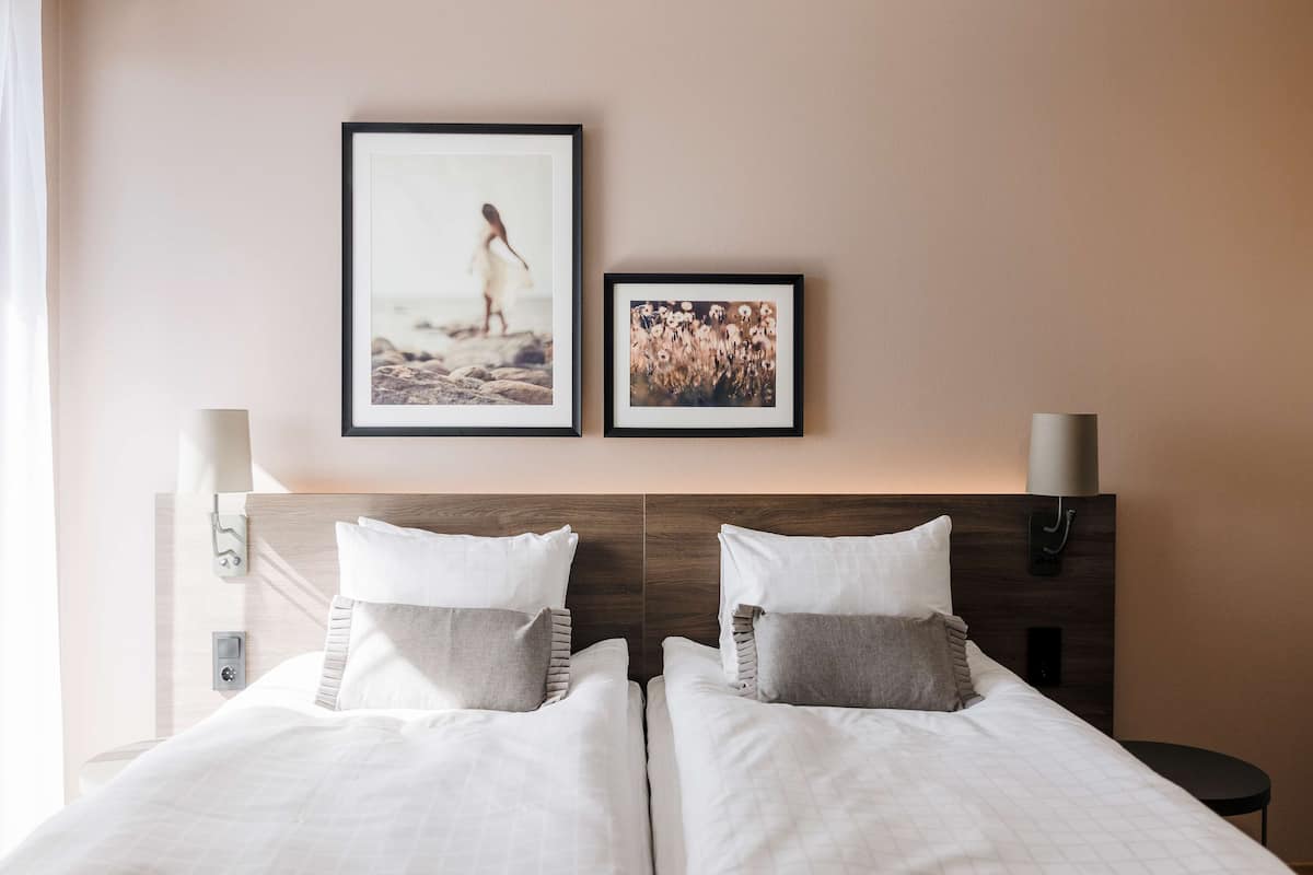 A double bed with two pillows, a headboard, and two wall-mounted lamps.