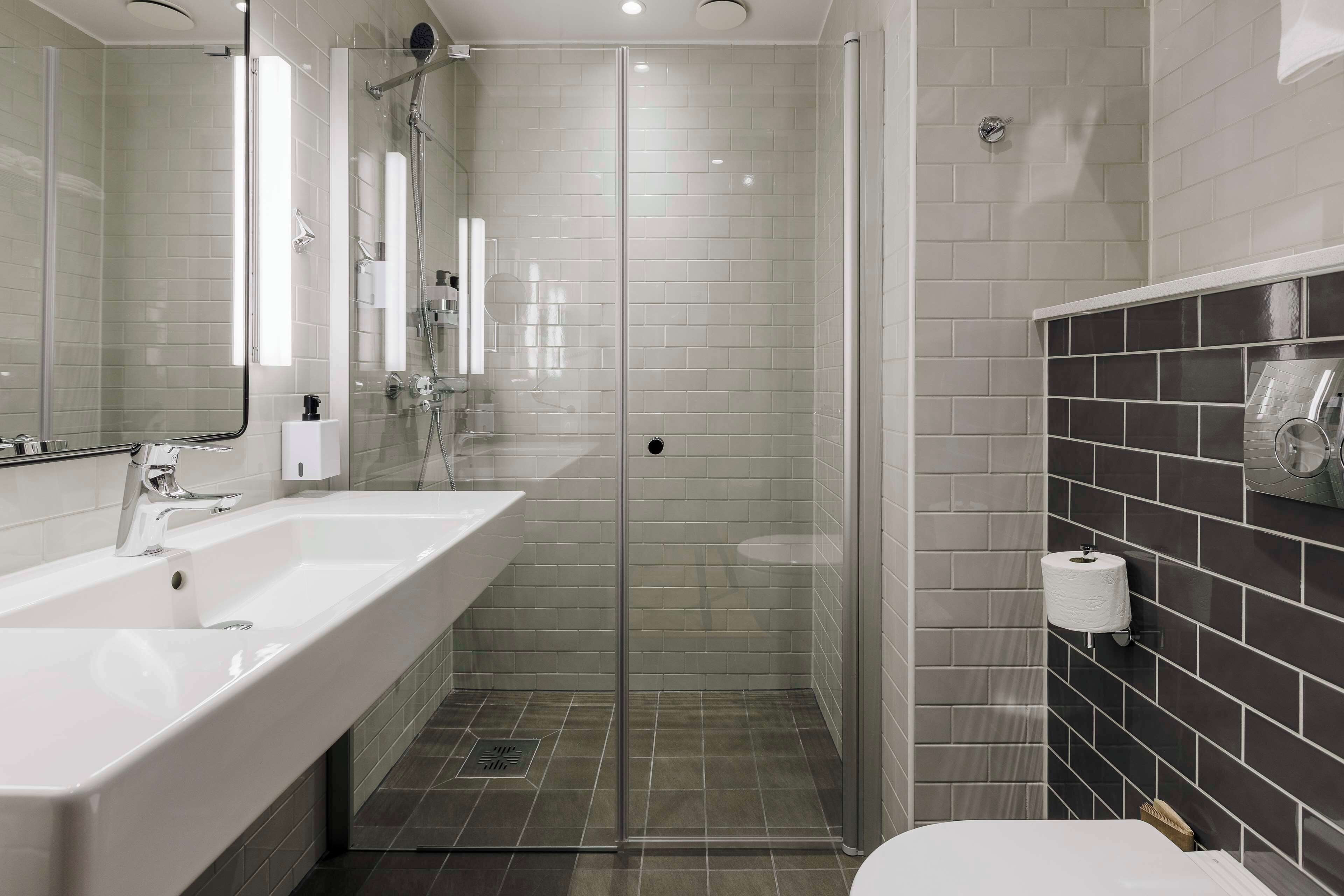 A modern bathroom with a glass-enclosed shower, a white sink, and a toilet.