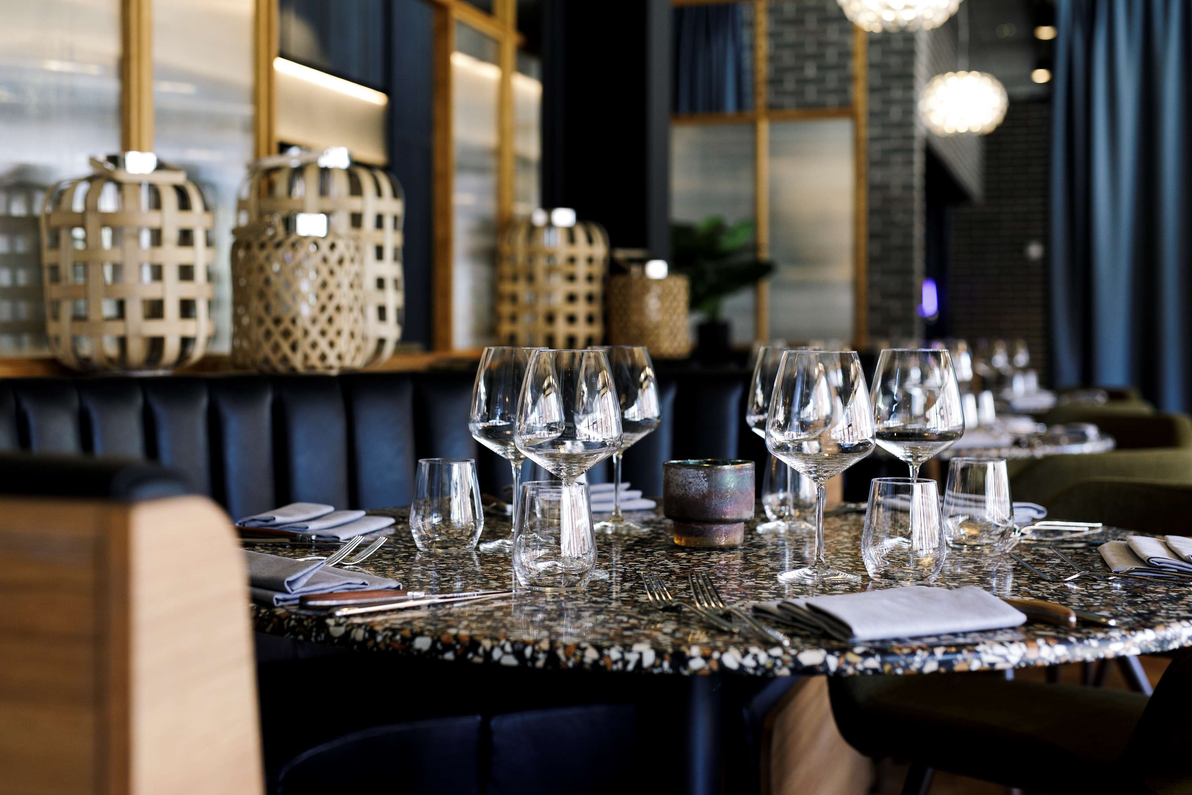 A restaurant table set with multiple wine glasses, a small decorative bowl, and neatly arranged cutlery.