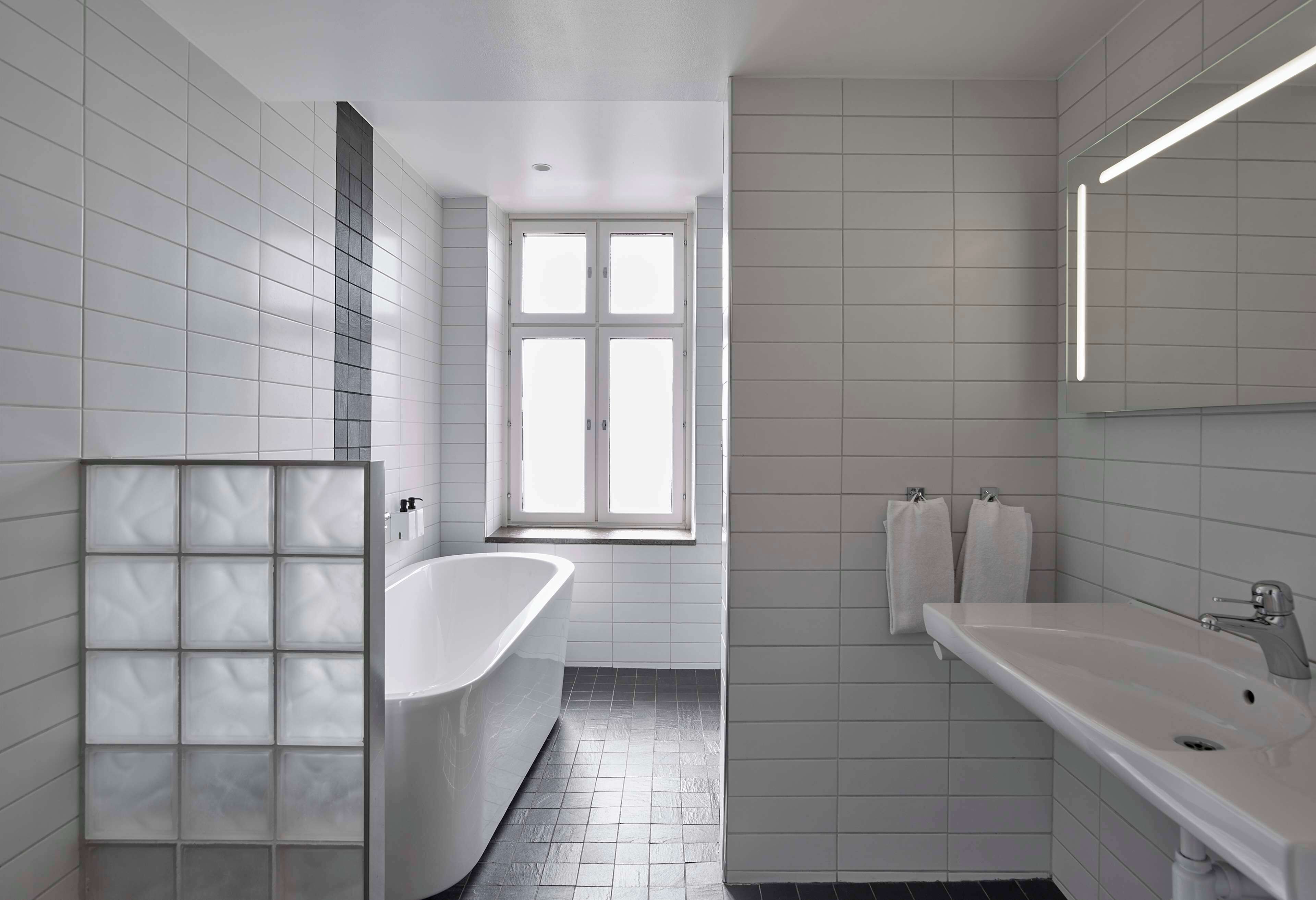 A modern bathroom with a freestanding bathtub, a large mirror, and a sink.