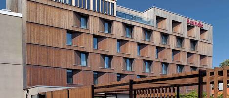 Stylish building with a grid-patterned facade and a covered outdoor area under a wooden pergola.