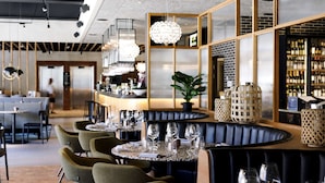 A modern restaurant with round tables, green chairs, and a bar area with a wine selection. - Scandic Strömmen (Norrköping)