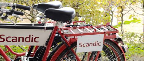A red bicycle with a basket and a sign that reads "Scandic."