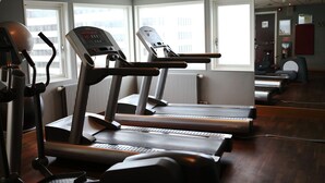 Academia com esteiras, bicicletas ergométricas e remo.