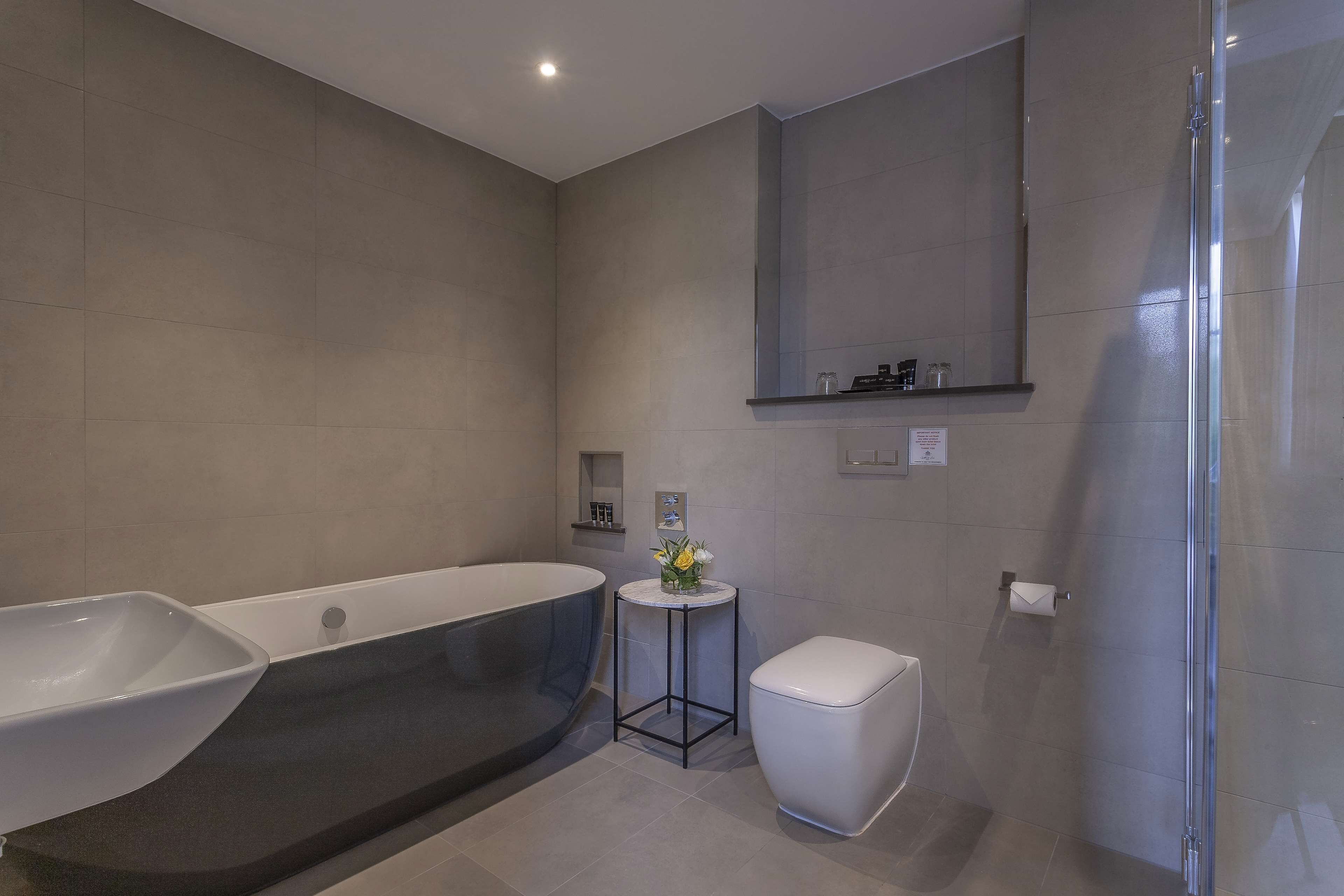 A modern bathroom with a freestanding bathtub, a toilet, and a glass-enclosed shower.