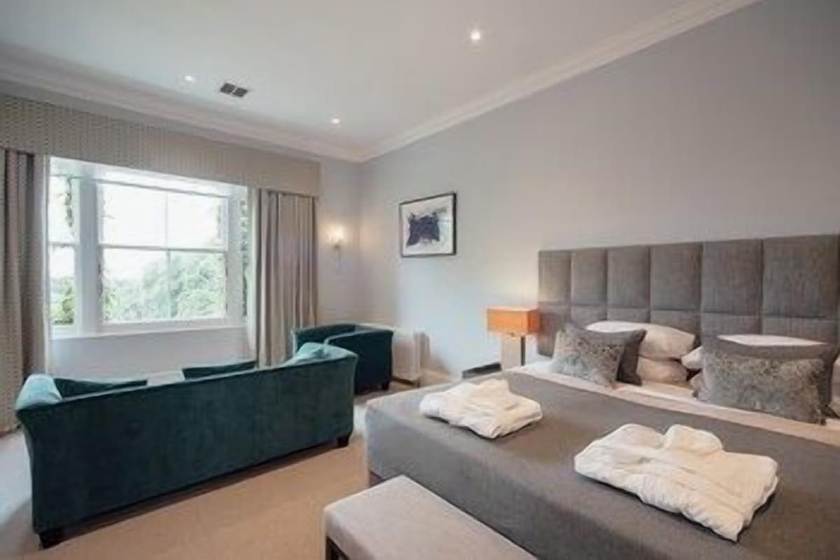 A hotel room with a bed, a sofa, a desk, and a window.