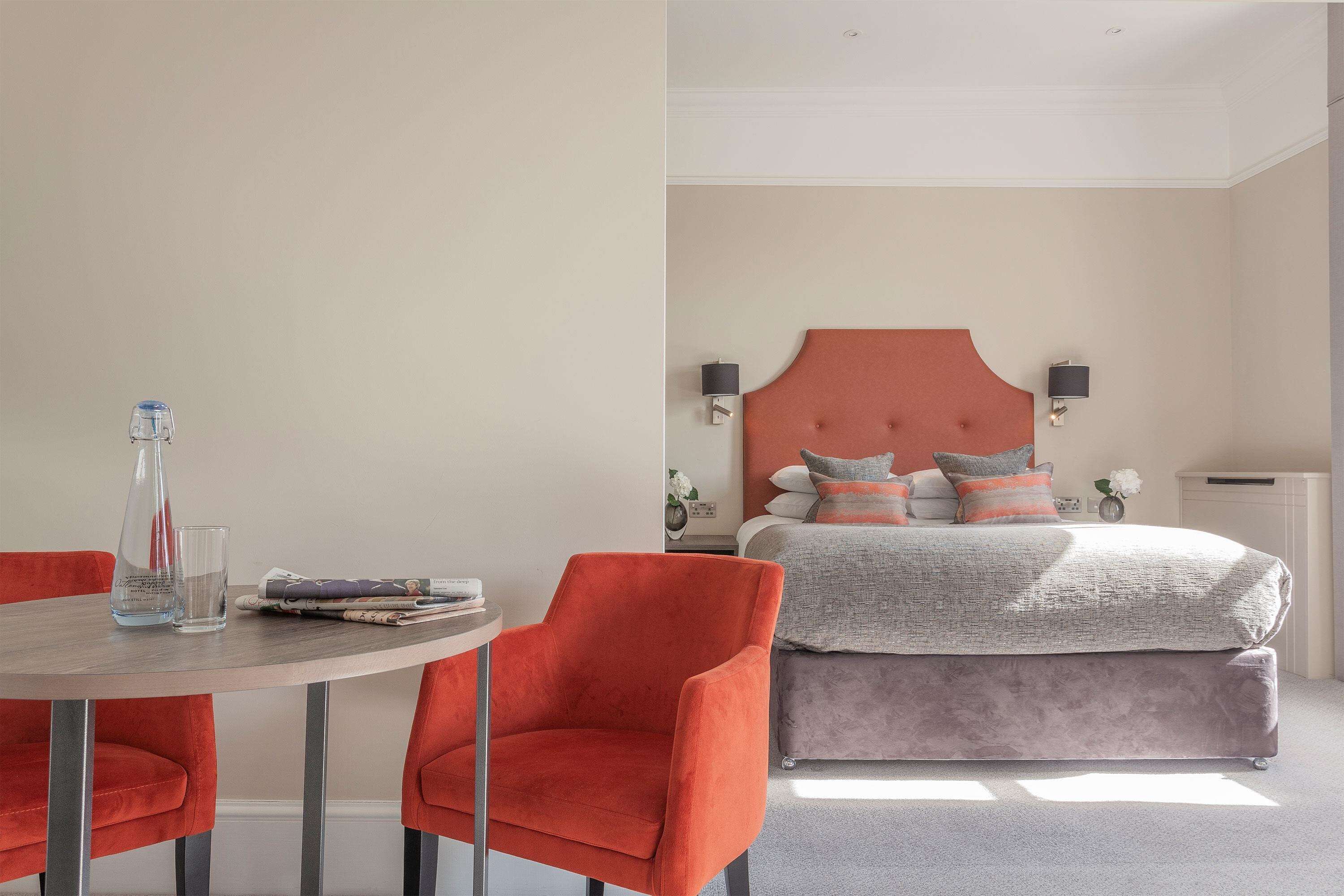 A modern bedroom with a large bed, two nightstands, and a round table with two chairs.