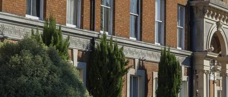 Un grand bâtiment en briques, doté de nombreuses fenêtres et agrémenté d’un jardin bien entretenu.