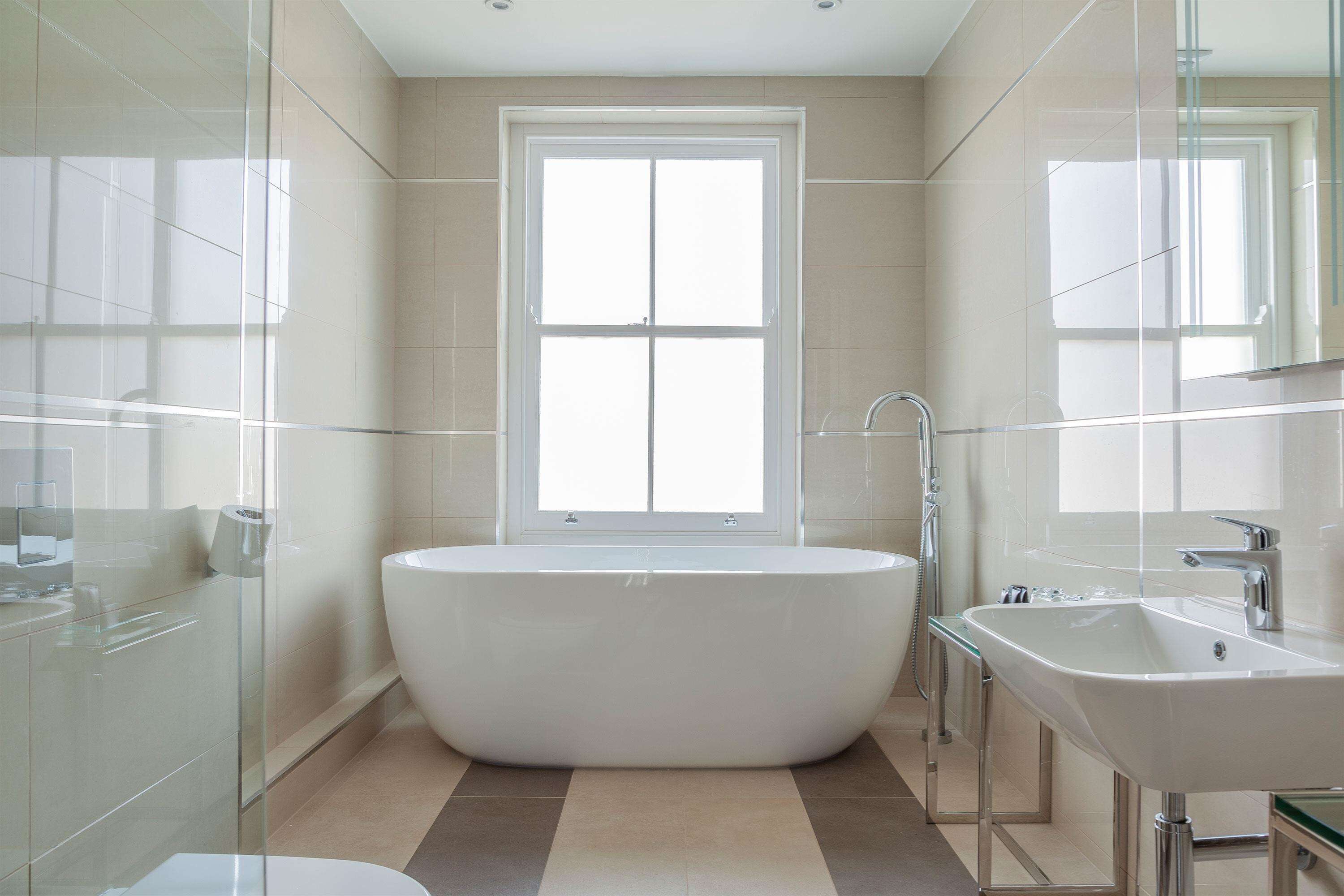 Une salle de bain moderne avec une baignoire sur pieds, une douche à parois de verre et un grand miroir au-dessus du lavabo.