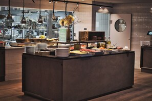 Enjoy a meal in our spacious buffet area, featuring a central island with a variety of food and beverages.