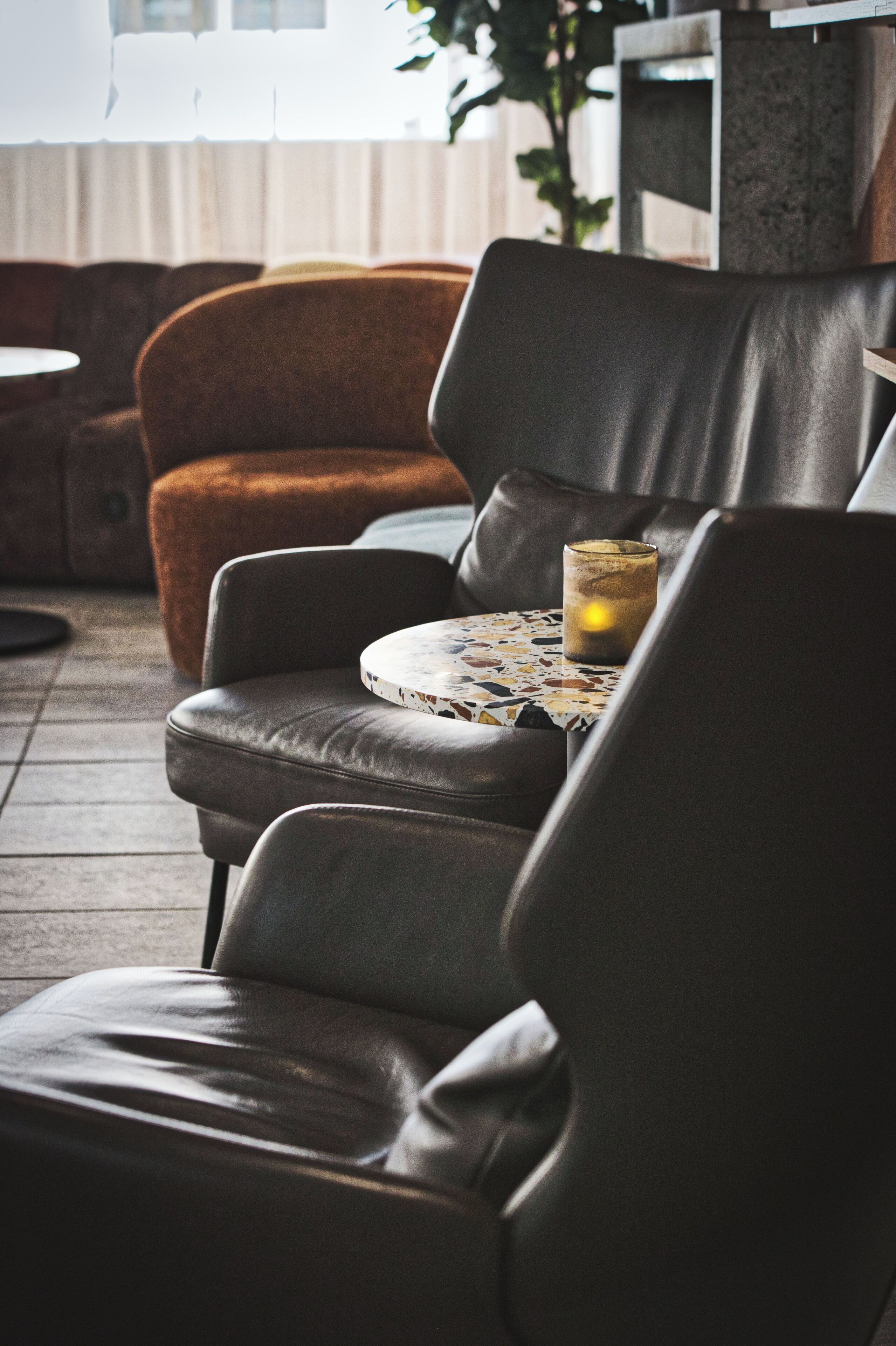 Un área de descanso con sillones de cuero y una mesa redonda con tablero de mosaico.