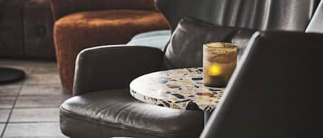 Un área de descanso con sillones de cuero y una mesa redonda con tablero de mosaico.