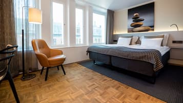 Habitación de hotel con cama, una silla, una lámpara y un cuadro en la pared.