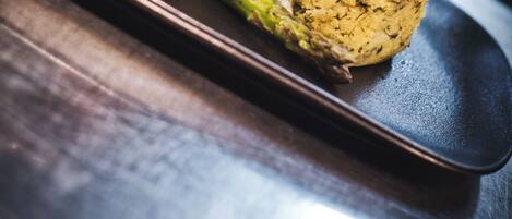 A close-up of a dish with grilled asparagus and a mound of rice topped with herbs, served on a black plate.
