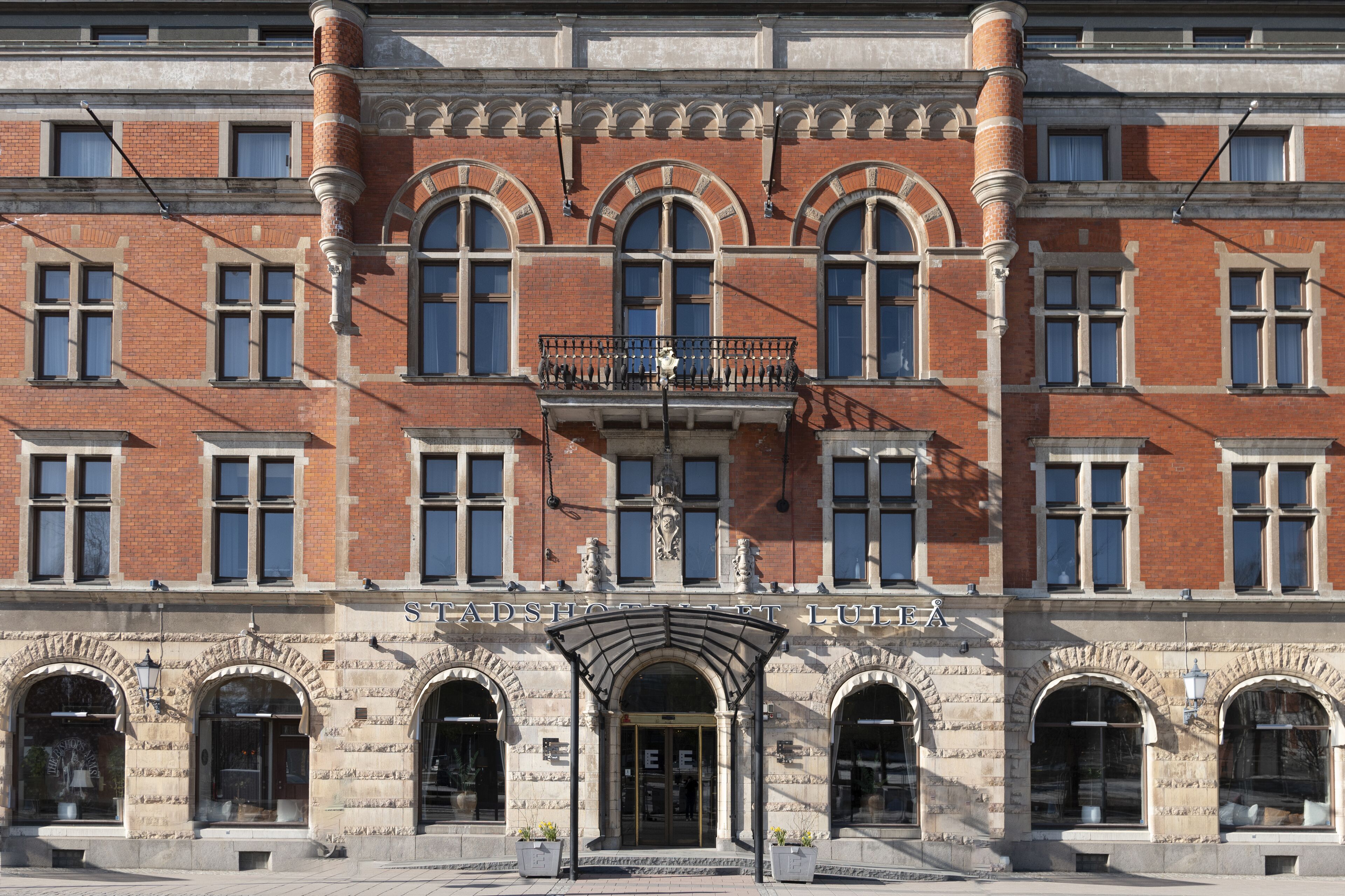 A historic building with a prominent entrance, large windows, and a balcony with railings.