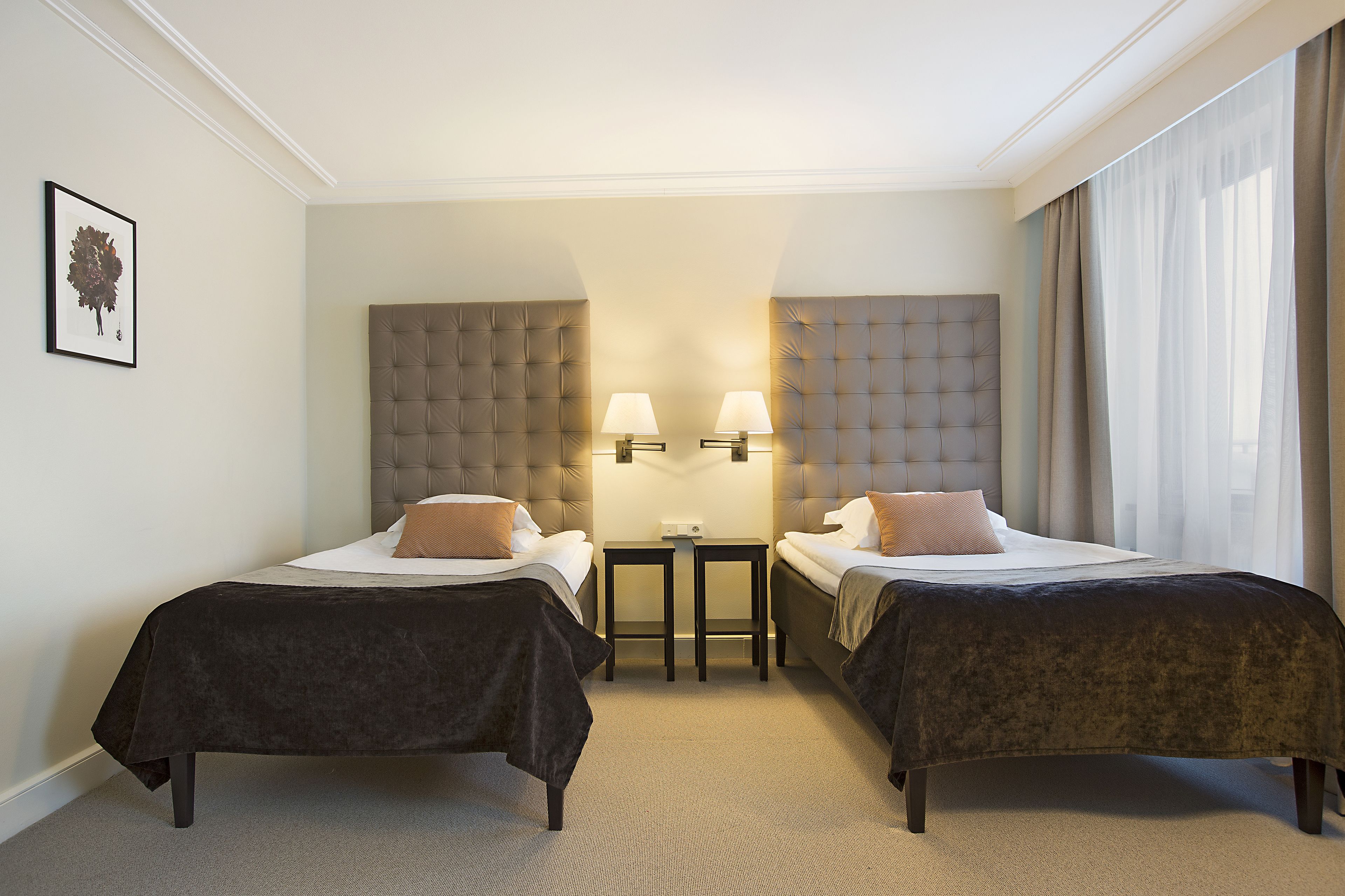 Une chambre d’hôtel avec deux lits, une petite table et une tête de lit.