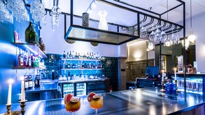 A bar area with a polished bar counter, shelves of bottles, and hanging light fixtures. - Scandic Stortorget (Malmö)