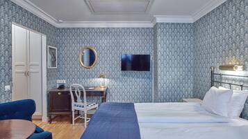 Una camera d'albergo con un letto, una scrivania con sedia, una televisione e un armadio.