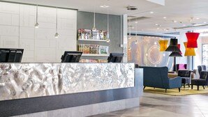 A reception area with a marble counter, magazines, and seating. - Scandic Klara (Stockholm)