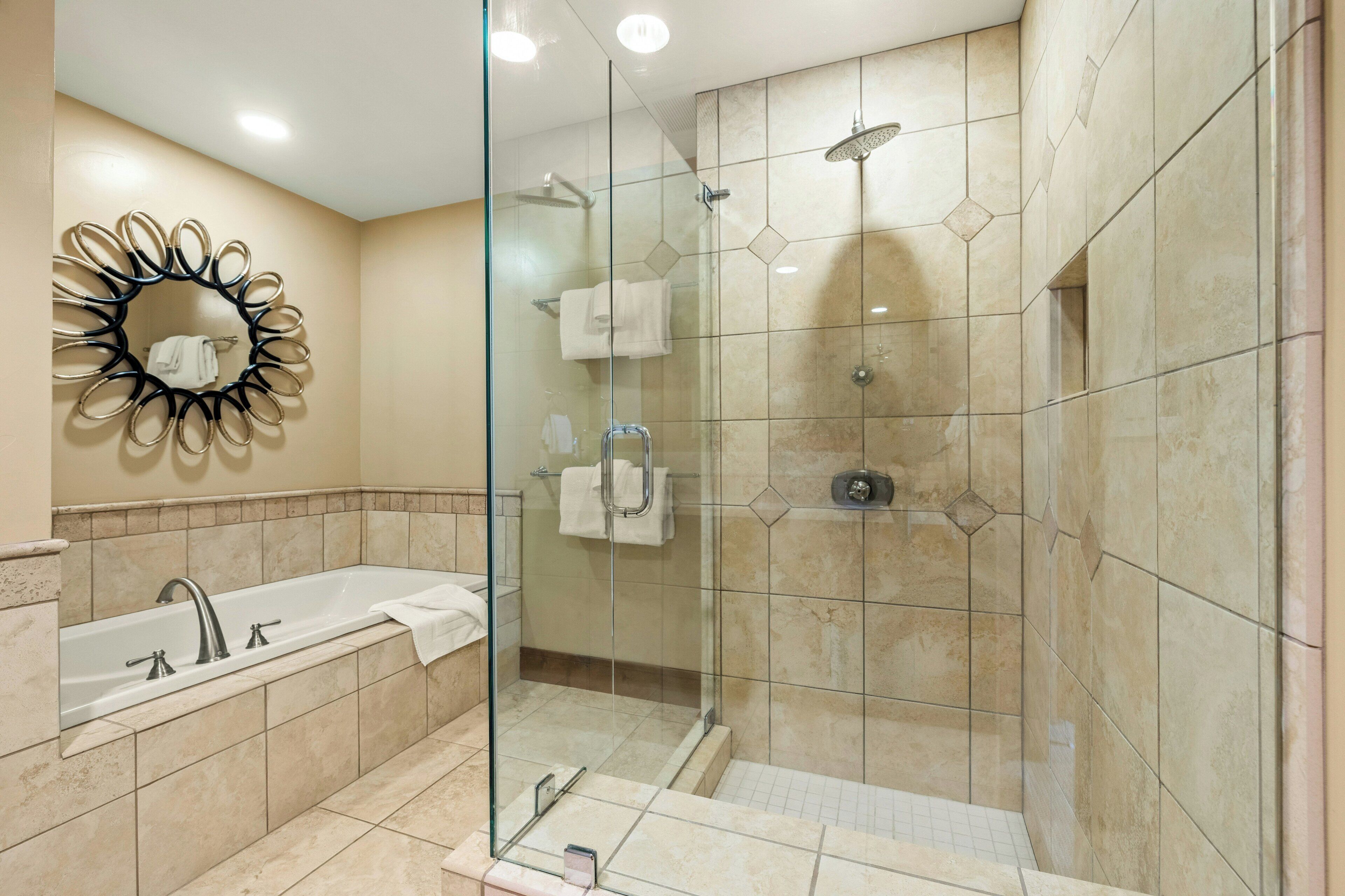 A modern bathroom with a glass-enclosed shower, a freestanding bathtub, and a decorative mirror.