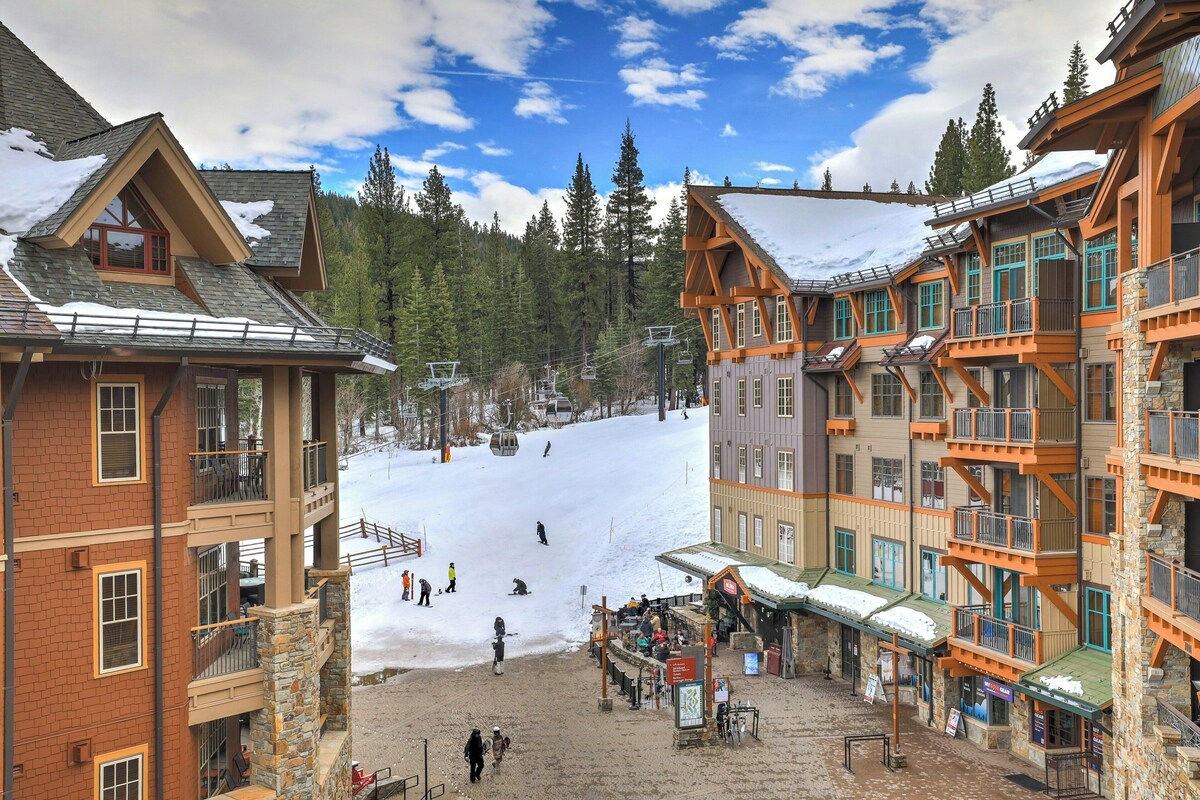 A ski resort with multi-story buildings, a ski lift, and a snow-covered slope.