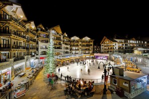 A multi-story hotel with a central ice rink, outdoor seating, and a Christmas tree. - Northstar Resort by Vail Resorts (Truckee)