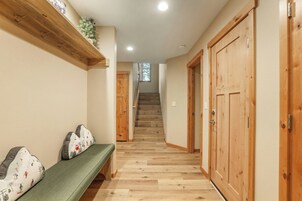 A hallway with a wooden bench, a staircase, and wooden doors.