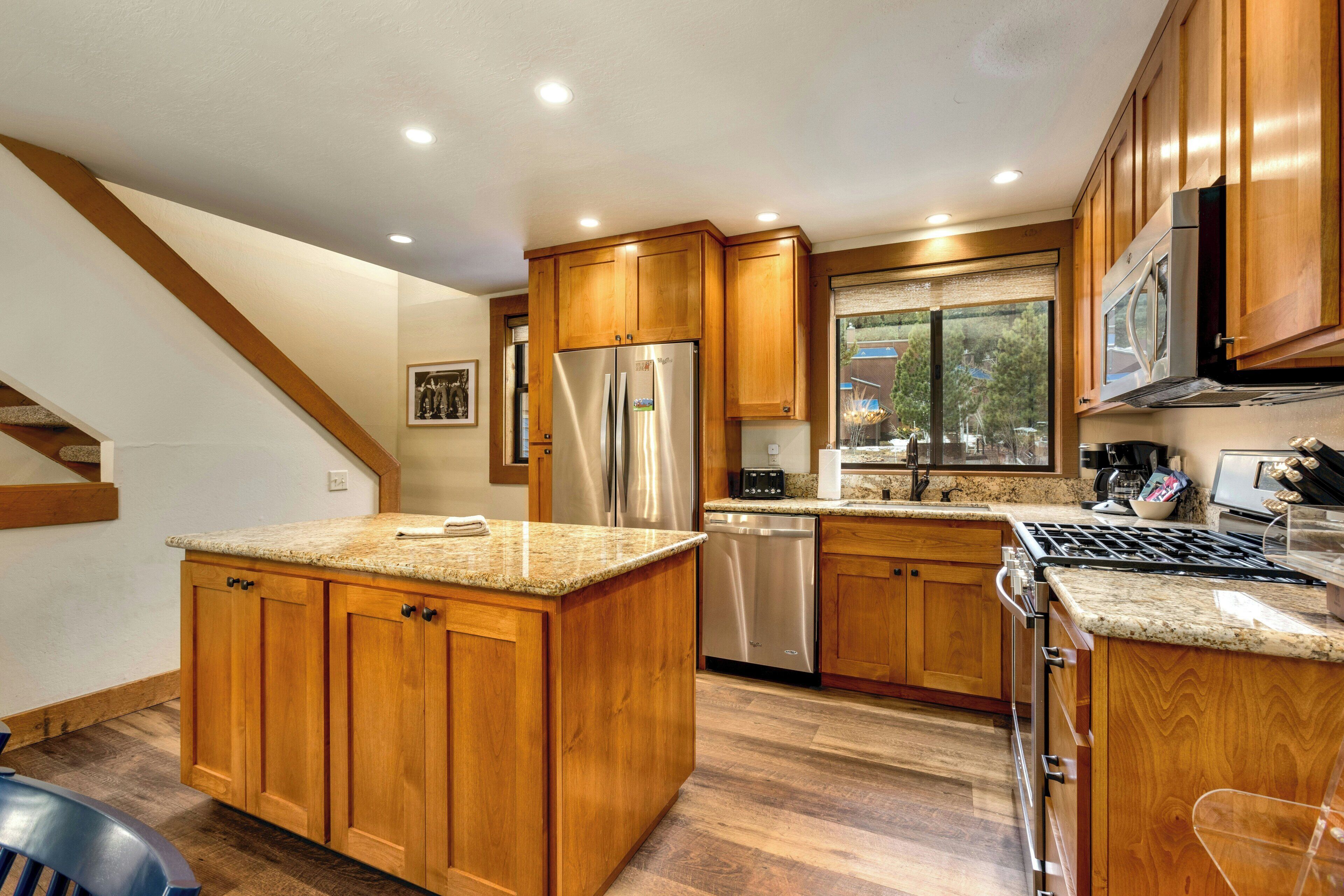 A kitchen with wooden cabinets, stainless steel appliances, and a granite countertop.