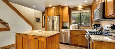 A kitchen with wooden cabinets, stainless steel appliances, and a granite countertop.