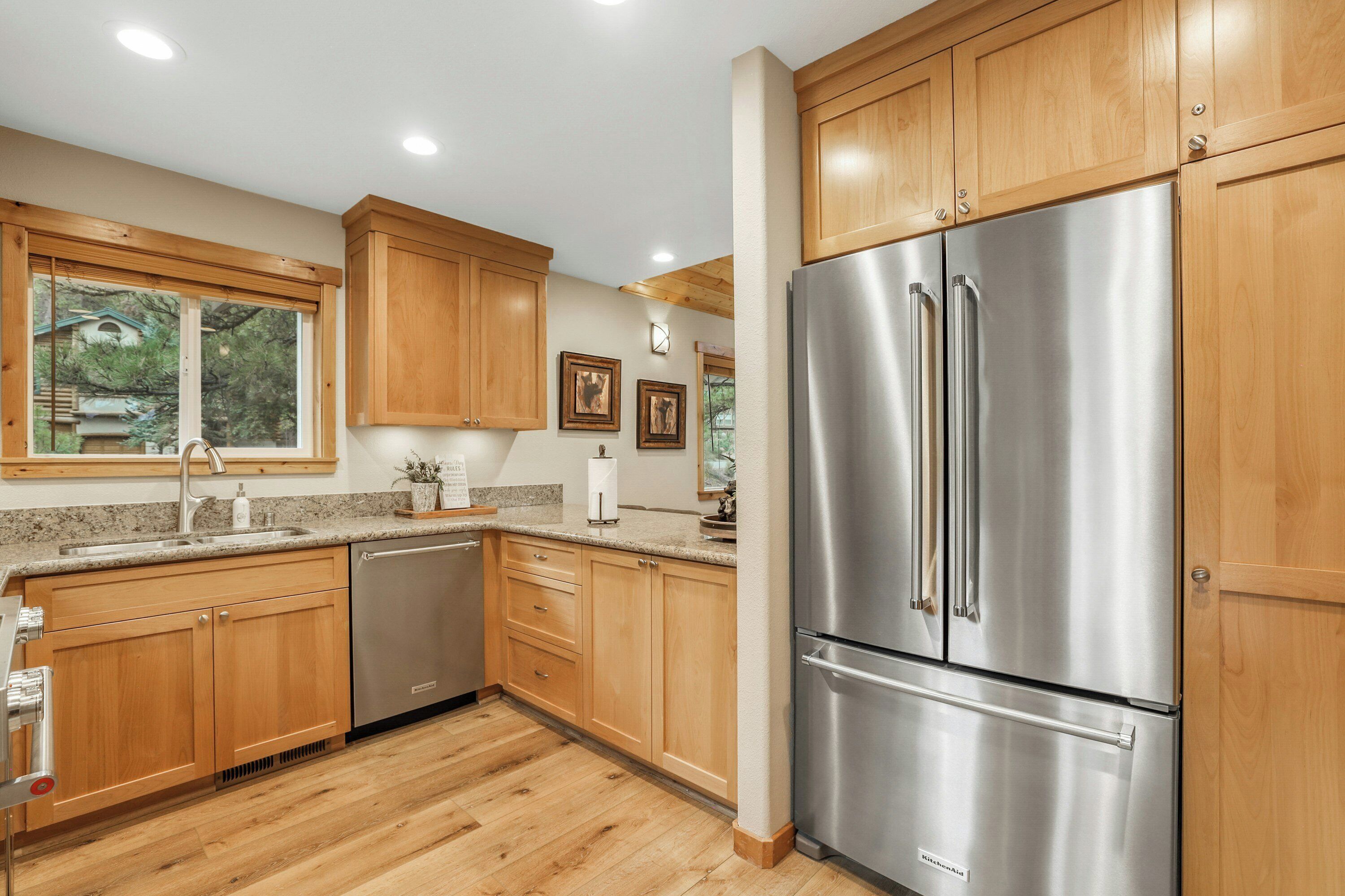 A modern kitchen with wooden cabinets, stainless steel appliances, and a granite countertop.