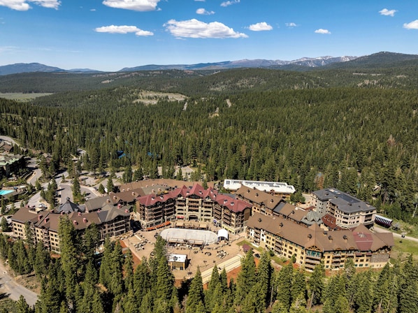 A lodge with multiple buildings, a central courtyard, and surrounding forested mountains.