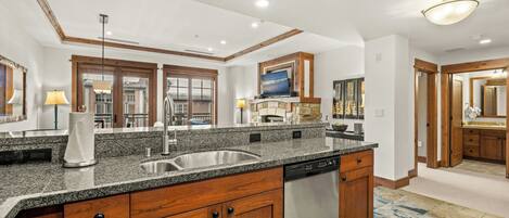 Una cocina moderna con encimeras de granito, electrodomésticos de acero inoxidable, armarios de madera y una isla grande.