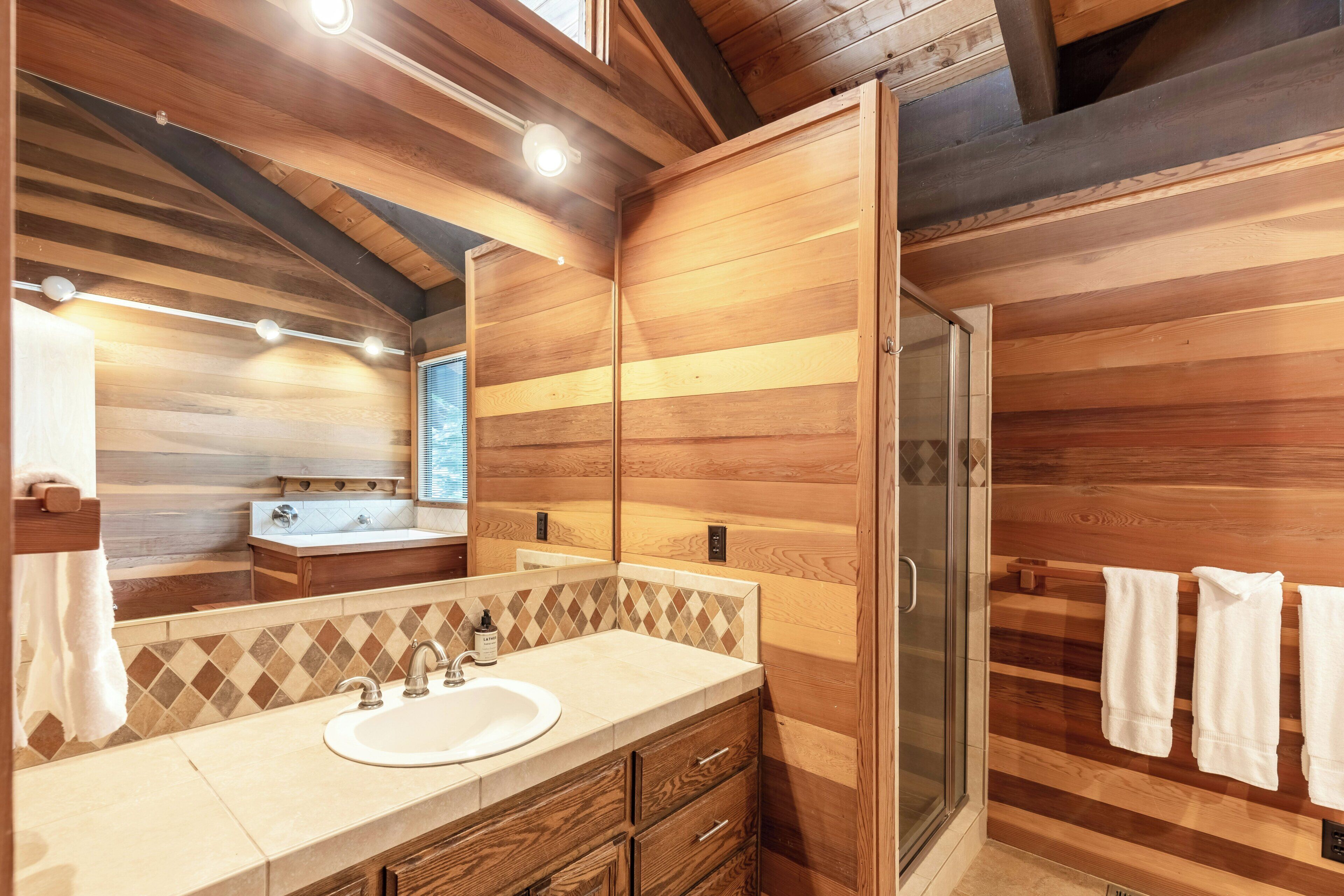 A wooden-paneled bathroom with a sink, mirror, and towel rack.