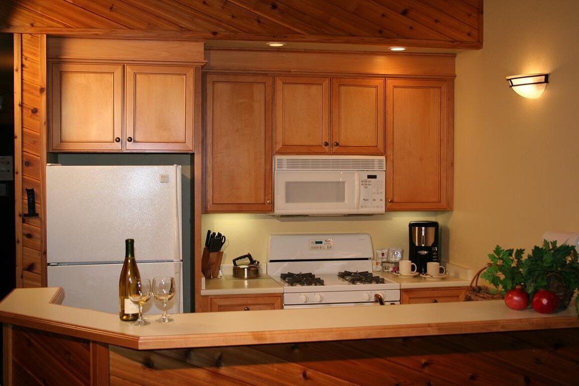 A kitchen with wooden cabinets, a white refrigerator, a microwave, a stove, and a coffee maker.