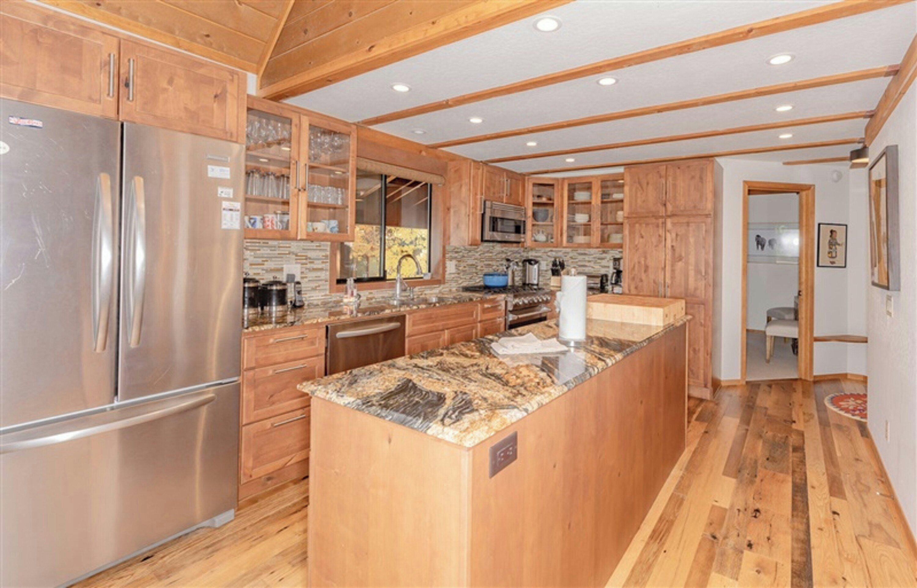 Een moderne keuken met houten kastjes, een granieten aanrechtblad, roestvrijstalen apparatuur en een betegelde achterwand.