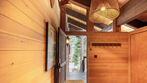 A wooden interior with a door leading to a view of trees.