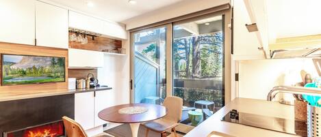 Una cocina moderna con televisión integrada, chimenea y comedor con mesa y sillas redondas.