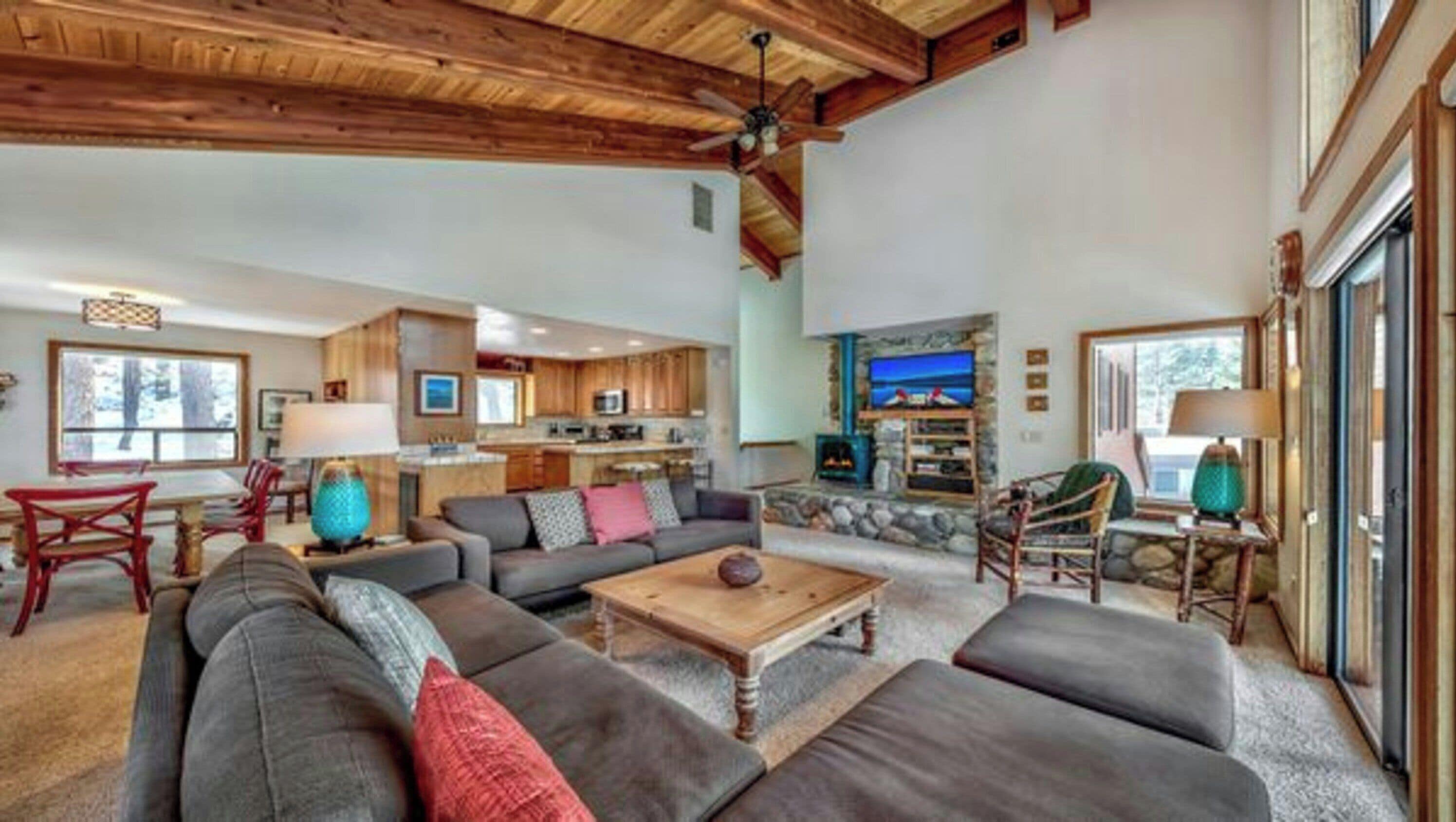 A spacious living room with a fireplace, a dining area with a table and chairs, and a kitchen in the background.