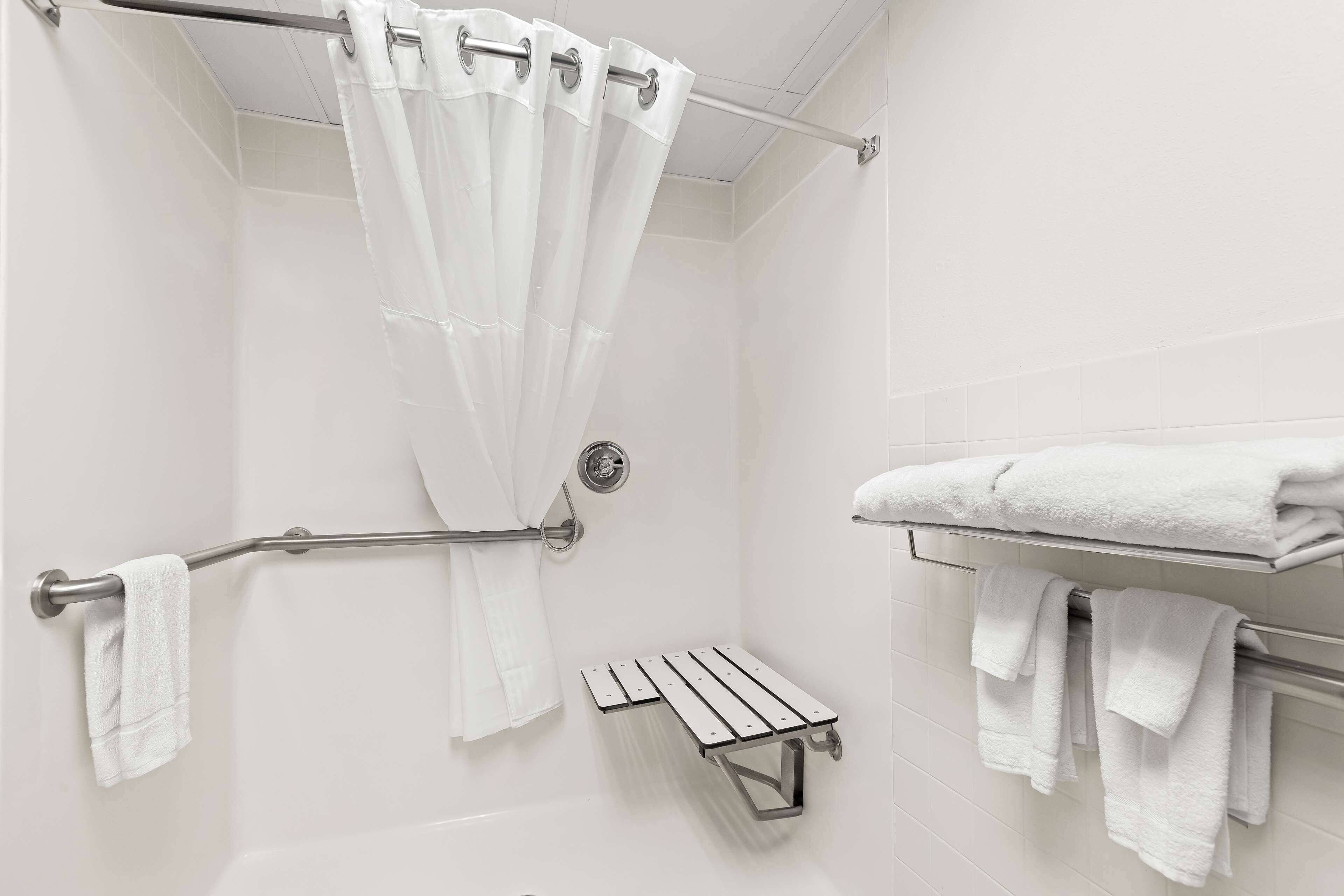 Une salle de bain équipée d’un rideau de douche, d’un porte-serviettes et d’une étagère à serviettes.