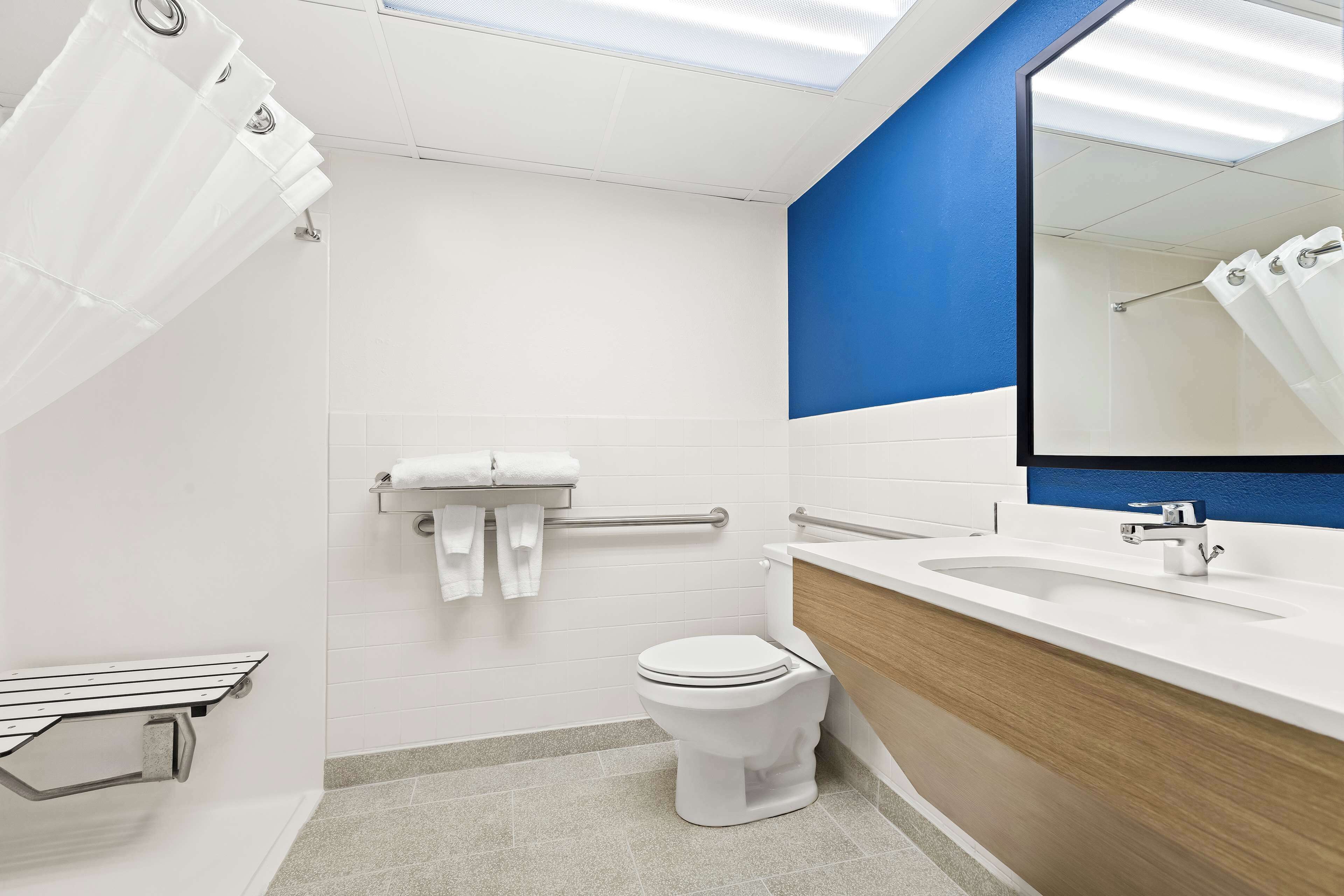 A modern bathroom with a white toilet, a sink with a mirror, and a shower area.