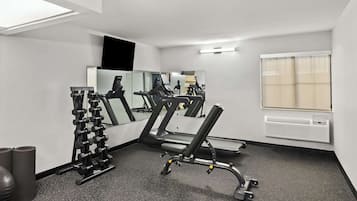 A gym with exercise equipment, a mirror, and a window.